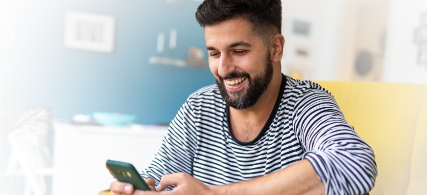 Man at home using his smart phone powered by Spectrum Mobile.