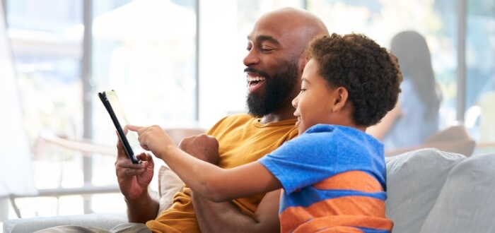 A father and his son looking at Spectrum Mobile customer reviews on a tablet.